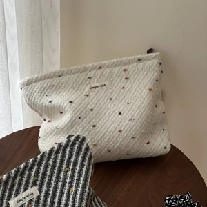 Detail of woven fabric pouches with zipper closures and simple wish label on a wood table