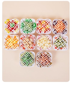 Bovenaanzicht van tien miniatuur fruitsalade modellen met witte saus en kleurrijke hars