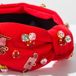 Dettaglio della fascia rossa annodata con strass colorati e ciondoli a cuore