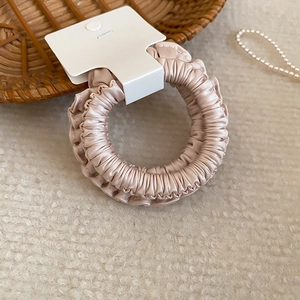 Gros plan sur le chouchou en satin doré champagne avec texture plissée élégante sur peluche