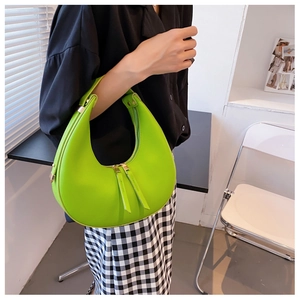 Detail of neon green leather crescent bag featuring dual zippers and elegant metallic hardware