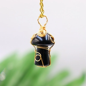 Macro detail of handmade wire-wrapped black crystal mushroom pendant on gold chain