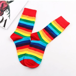 Flat lay of colorful rainbow striped crew socks with red ribbed cuffs on white background