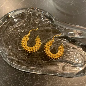 18K gold plated hoop earrings with granulated texture on a premium stone background