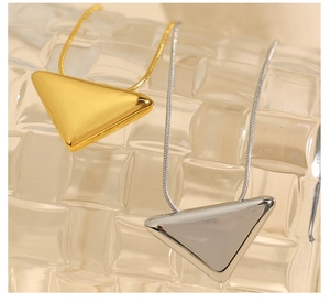 Close-up of minimalist inverted triangle pendants in gold and silver finish