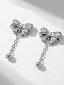 Detail of silver butterfly earrings with chain balls on a white textured background
