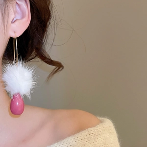 Dettaglio dell'orecchino con morbida palla di pelo bianca e pendente a goccia rosa
