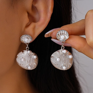 Silver shell earrings with pearls on a model, showing luxury metal texture and design
