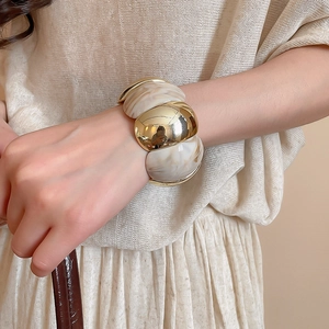 Close-up of geometric acrylic resin segments and gold metal arc links on the wrist
