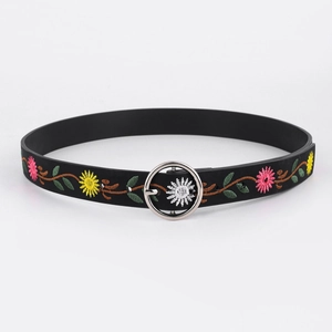 Close-up of black leather belt with colorful floral embroidery and silver round buckle