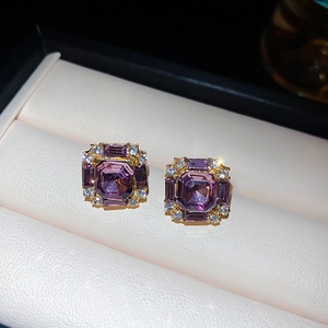 Macro shot of square purple zircon earrings with halo stones in a cream jewelry box