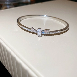 Détail d'un bracelet nœud argenté avec micro-pavé de zircons sur support en cuir blanc