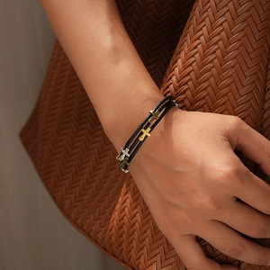 Détail d'un bracelet multicouche en cuir avec des croix en métal vintage au poignet