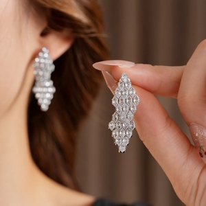 Macro detail of silver geometric rhombus earrings with sparkling zircon crystals