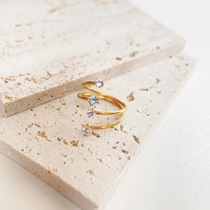 Macro detail of triple-layered gold-plated spiral ring with sparkling zircon stones