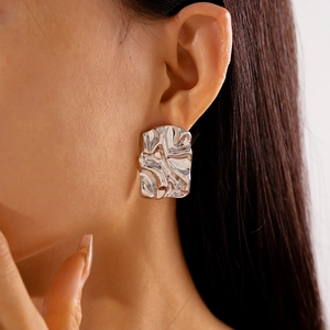 Close-up of silver irregular square studs with a molten metal texture and mirror finish