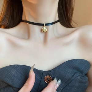Detailed close-up of a black satin choker featuring a gold compass star pendant with a crystal