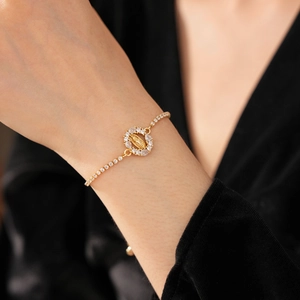 Détail du bracelet doré avec pendentif de la Vierge Marie orné de pierres de zircone