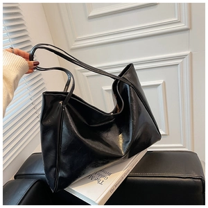 Detail of black glossy wrinkled leather tote bag placed on vintage books in soft light