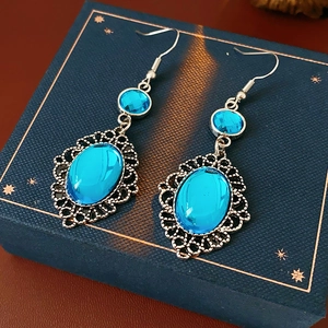 Macro detail of oval blue resin earrings set in vintage silver-tone filigree metalwork