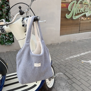 Detail of grey fuzzy fleece tote bag hanging on a vintage scooter handle outdoors