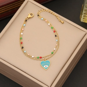 Detail view of a gold double-layer chain with colorful beads and a blue evil eye heart charm