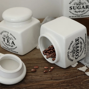Nordic white ceramic canisters set for tea, coffee and sugar on wooden surface