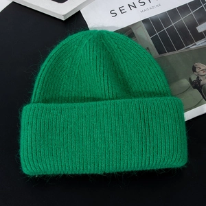 Detail of bright green knit beanie with thick mohair texture and ribbed pattern on magazine