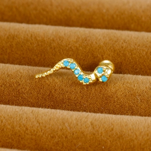 Vue macro d'une boucle d'oreille serpent dorée avec pierres bleues en boîte de velours