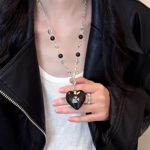 Macro shot of gothic black heart pendant necklace with silver cross and matching ring
