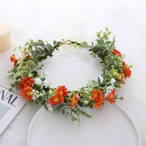 Detailed shot of orange daisy and white babys breath floral wreath with green leaves