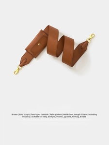 Close-up of brown textured leather bag strap with gold clasps and mini pouch detail