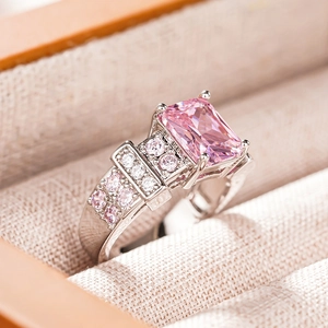 Macro shot of rectangular pink gemstone ring with four-prong setting in beige jewelry box