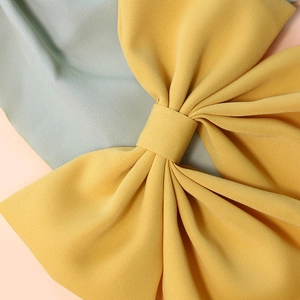 Detailed macro view showing the fabric texture of a yellow bow hair clip for children