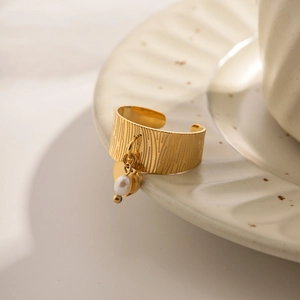 Detail of 18K gold stainless steel ring featuring vertical textures and a pearl pendant
