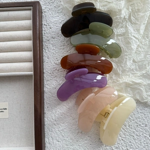 Flat lay of colorful jelly-tone crescent hair claws on a white textured surface
