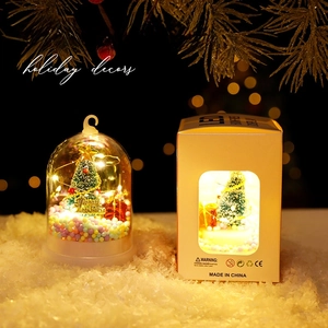 Christmas tree glass dome LED ornament with gift box in a warm festive holiday setting