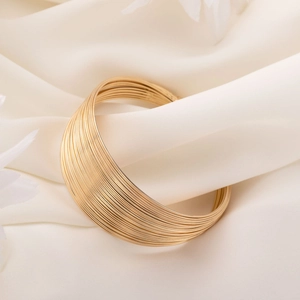 Elegant gold multi-layered stackable bangle on white silk fabric background