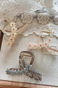 Detailed view of elegant crystal flower claw clips in pink, champagne, and blue colors