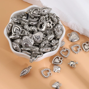 Assorted Y2K style silver heart pendants for DIY jewelry making in a white bowl