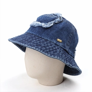 Detailed close-up of blue denim bucket hat with distressed frayed edges and metal label