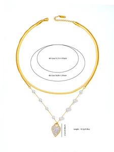 Dettaglio della collana a doppio strato in acciaio dorato con pendente a cuore e perle