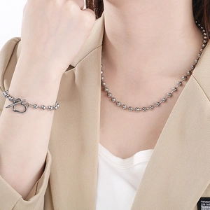 Macro detail of silver bead necklace and heart OT buckle bracelet on model