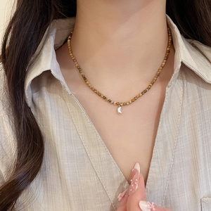 Detail of 18K gold plated tiger eye stone necklace with irregular moon pendant on model