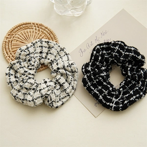 Set of black and white tweed scrunchies displayed on a beige table for hair styling