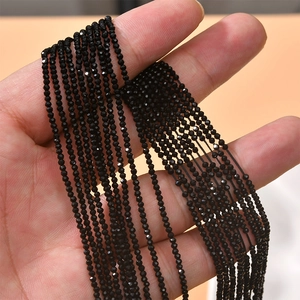 Close-up of black 2mm faceted crystal glass wheel beads held in hand for DIY jewelry