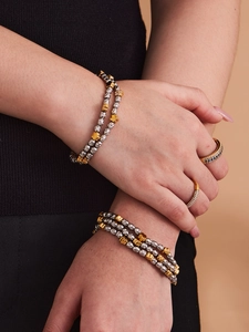 Detail of beaded gold and silver bracelets with hammered texture and diamond rings