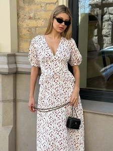 Détail de robe fleurie avec col en V, manches bouffantes et volants à la taille