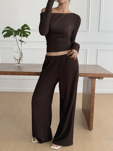 Detail showing the pleated fabric texture of a brown long sleeve top and wide leg pants