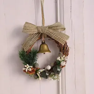 Détail d'une couronne de Noël de 16cm avec pommes de pin, cloche et nœud rayé